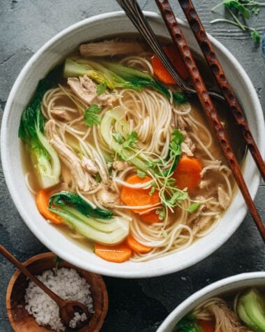 Bowl of noodle soup with shredded chicken, carrot and baby bok choy